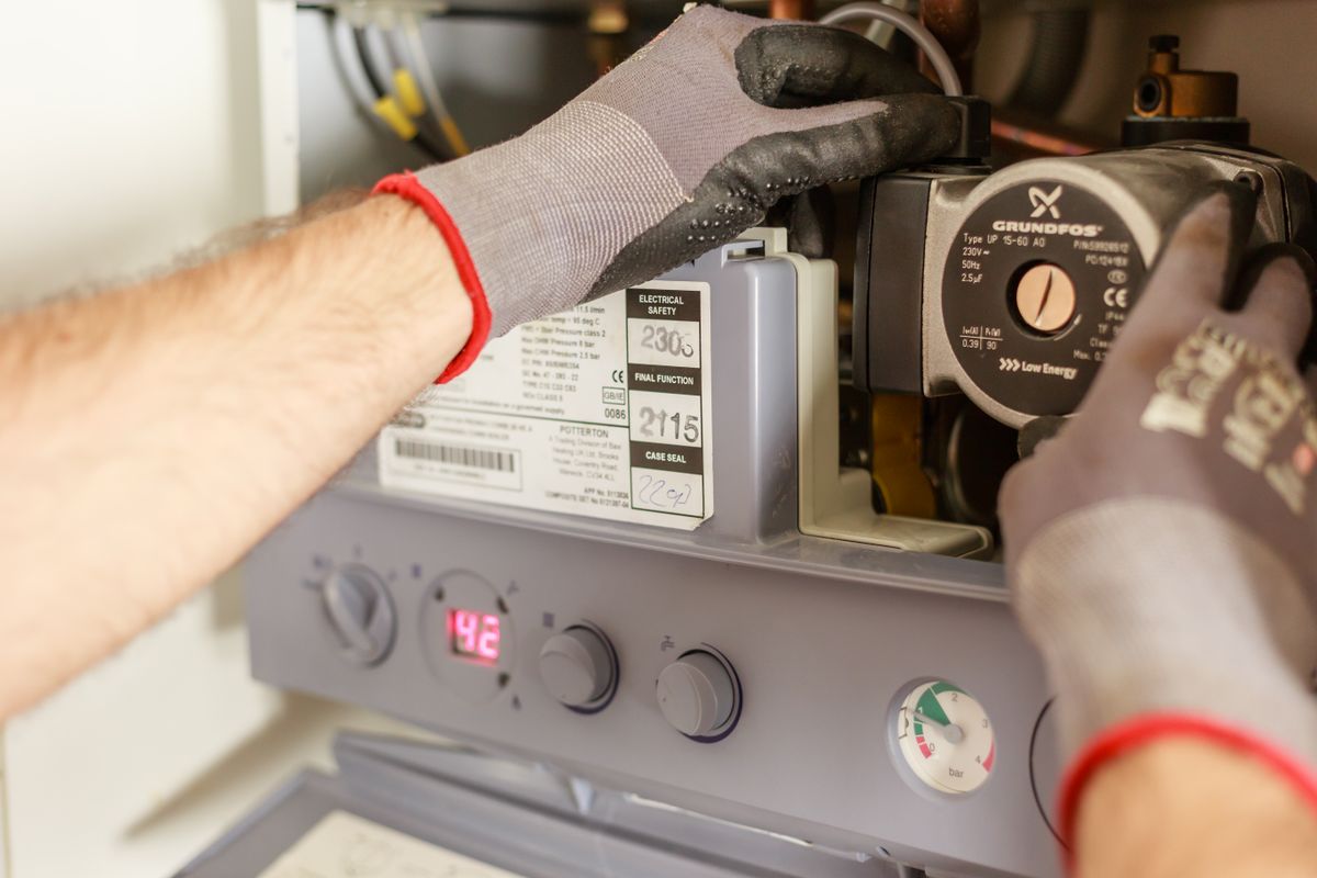 Stock close-up of hands checking a residential boiler control